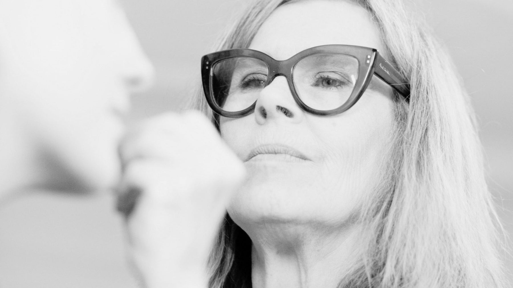 SAPPHO makeup brand founder JoAnn Fowler applying makeup on someone, up close in black and white